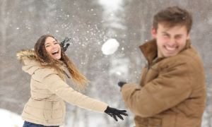 Woman throwing snowball at man