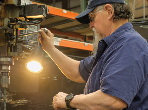 Man works with machinery in shop.