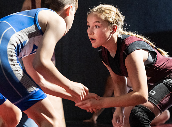 A girl matches up against a boy in a school wrestling match