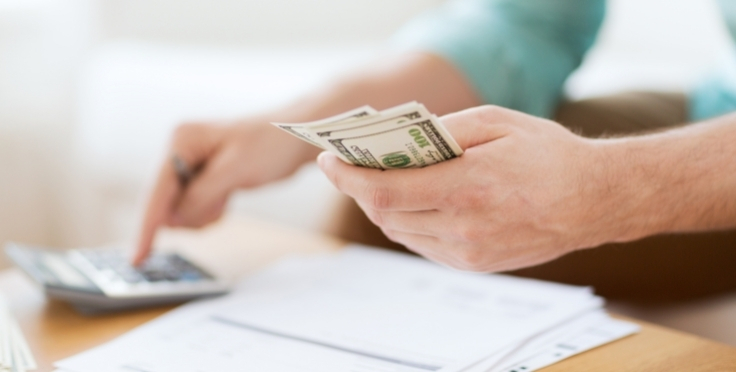 Man using a calculator and holding cash